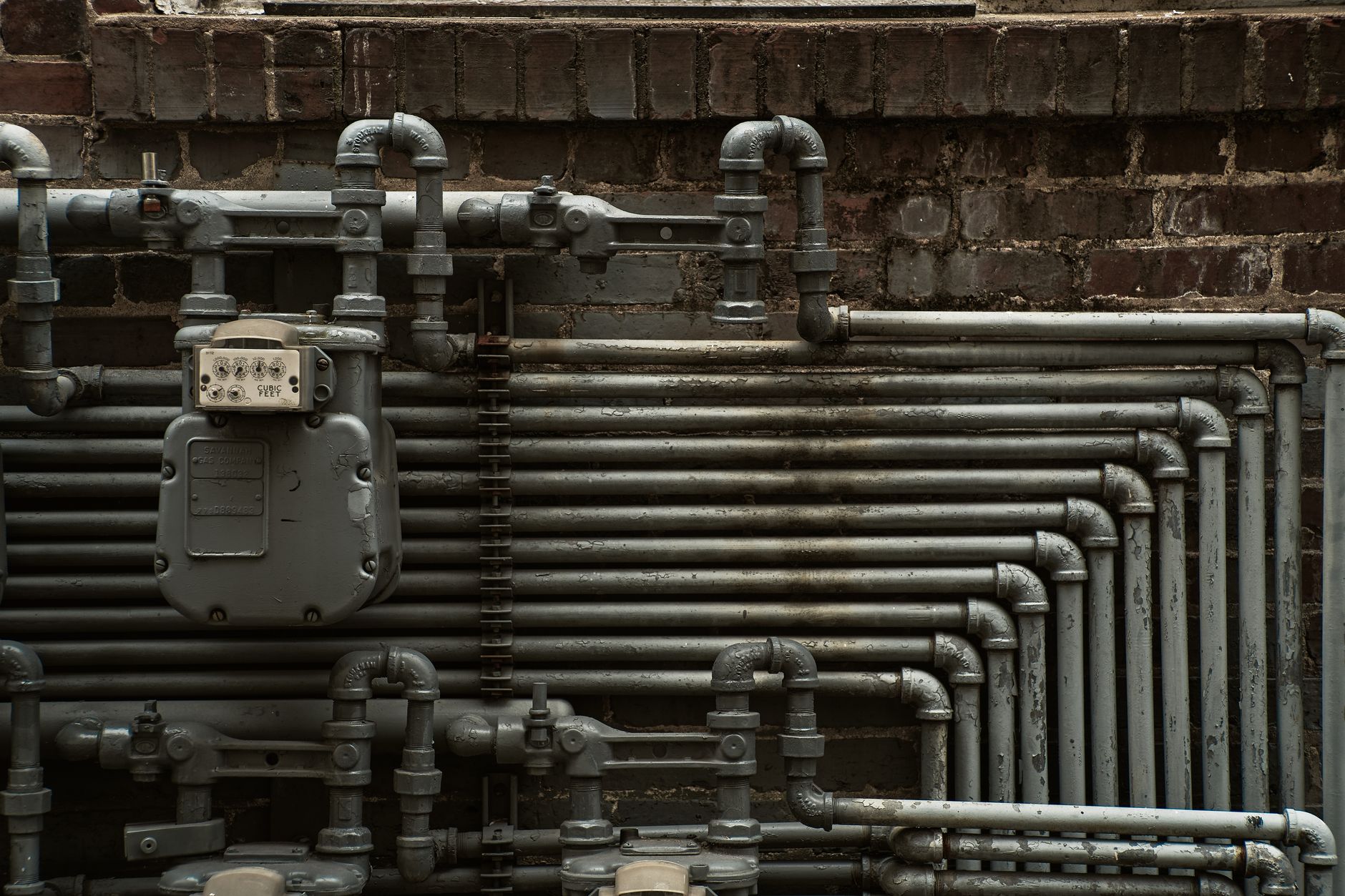 Industrial pipes and a meter mounted on a brick wall